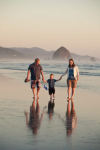 Sunset photo of family walking on the beach in Cannon Beach, Oregon.