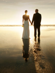 Married couple on beach during sunset.